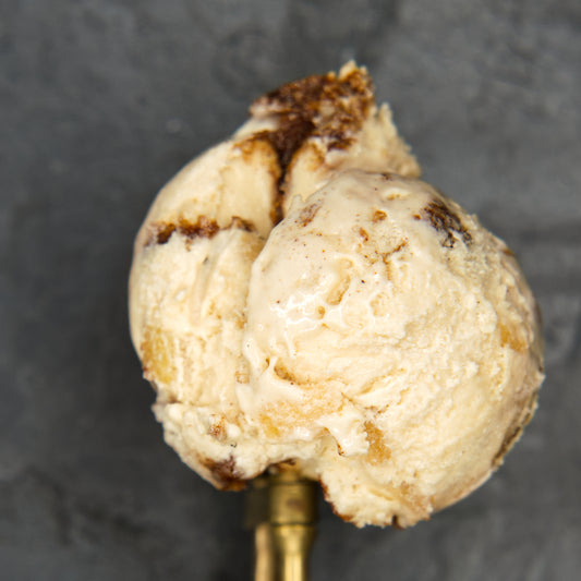 Scoop of ice cream with a cinnamon swirl on a dark background.