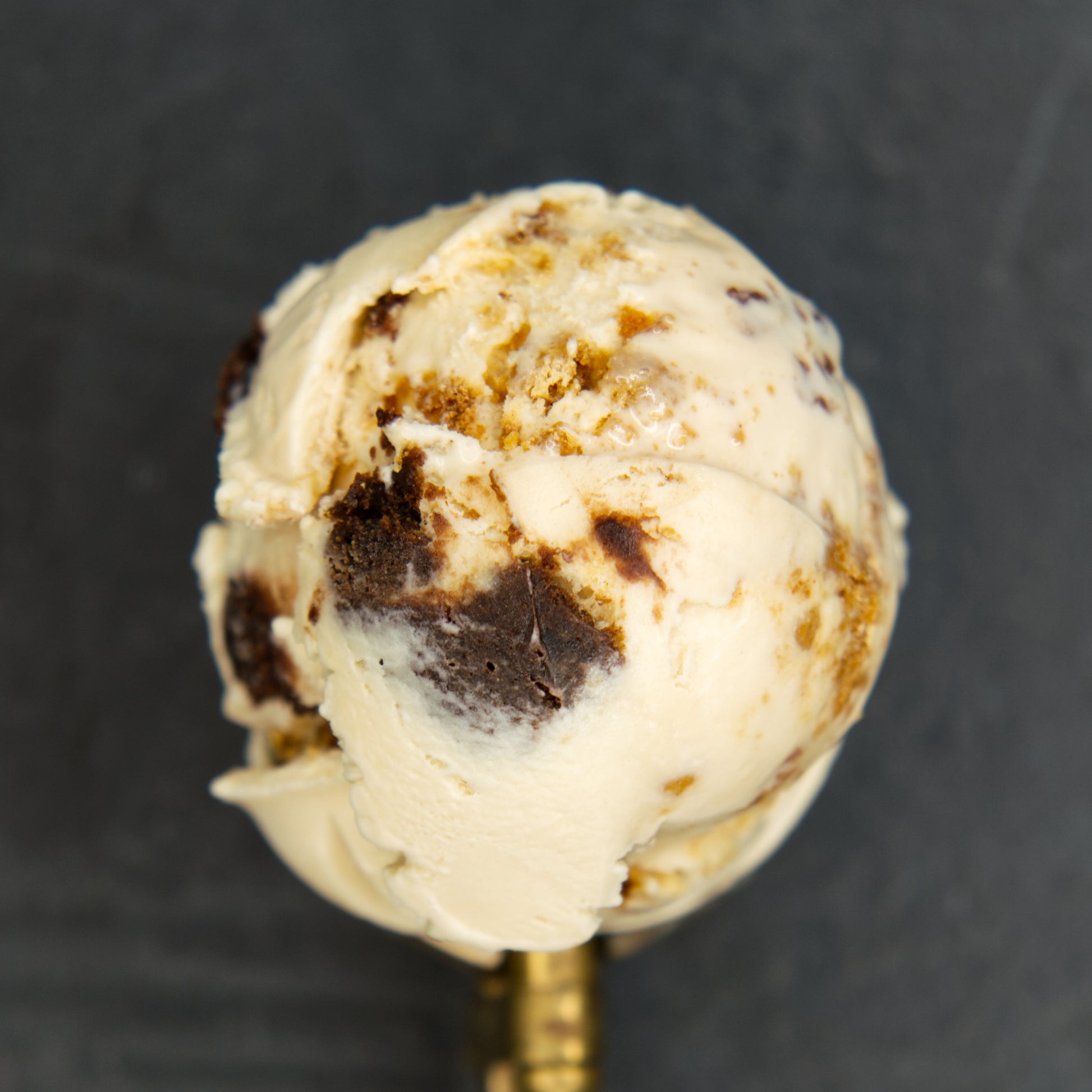 Close-up of a scoop of ice cream with brownie chunks on a dark background