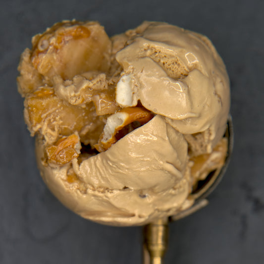 Close-up of a scoop of ice cream with pieces of toffee in it against a dark background