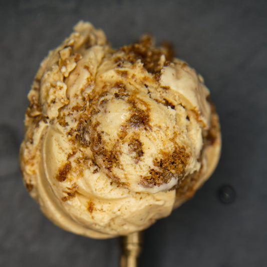 Close-up scoop of ice cream with pieces of cookies against a dark background.