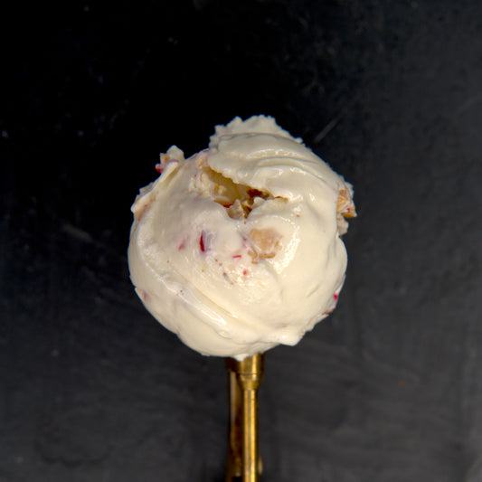 Ice cream scoop on a gold spoon against a dark background