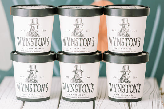 Six containers of Wynston's Ice Cream Co. on a wooden surface with a blurred background.